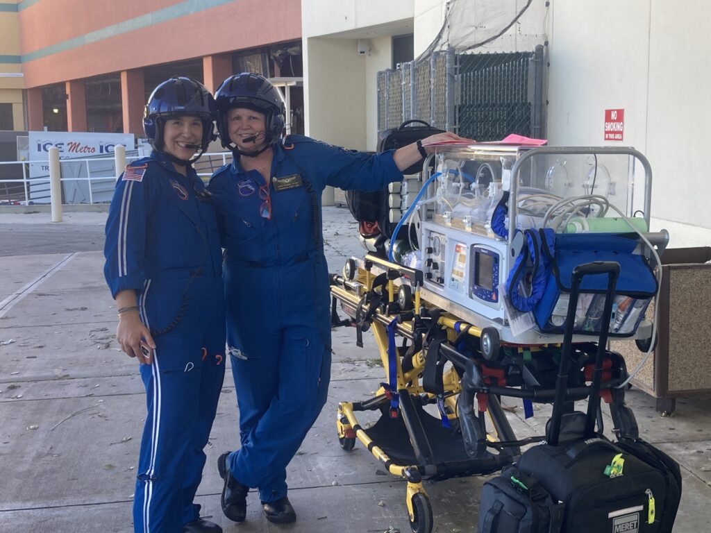 Airborne nurses posing next to a transport incubator