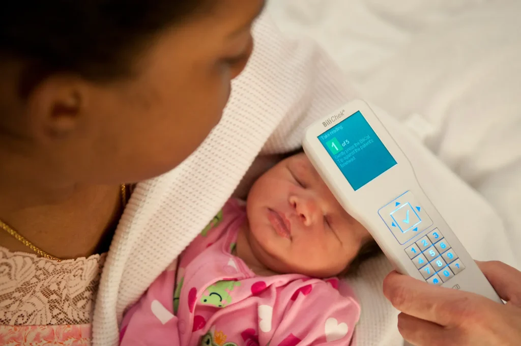 mother checking infant forehead with device