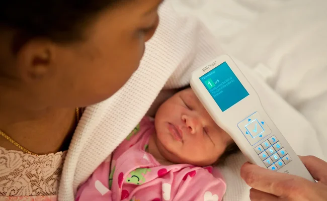 mother checking infant forehead with device